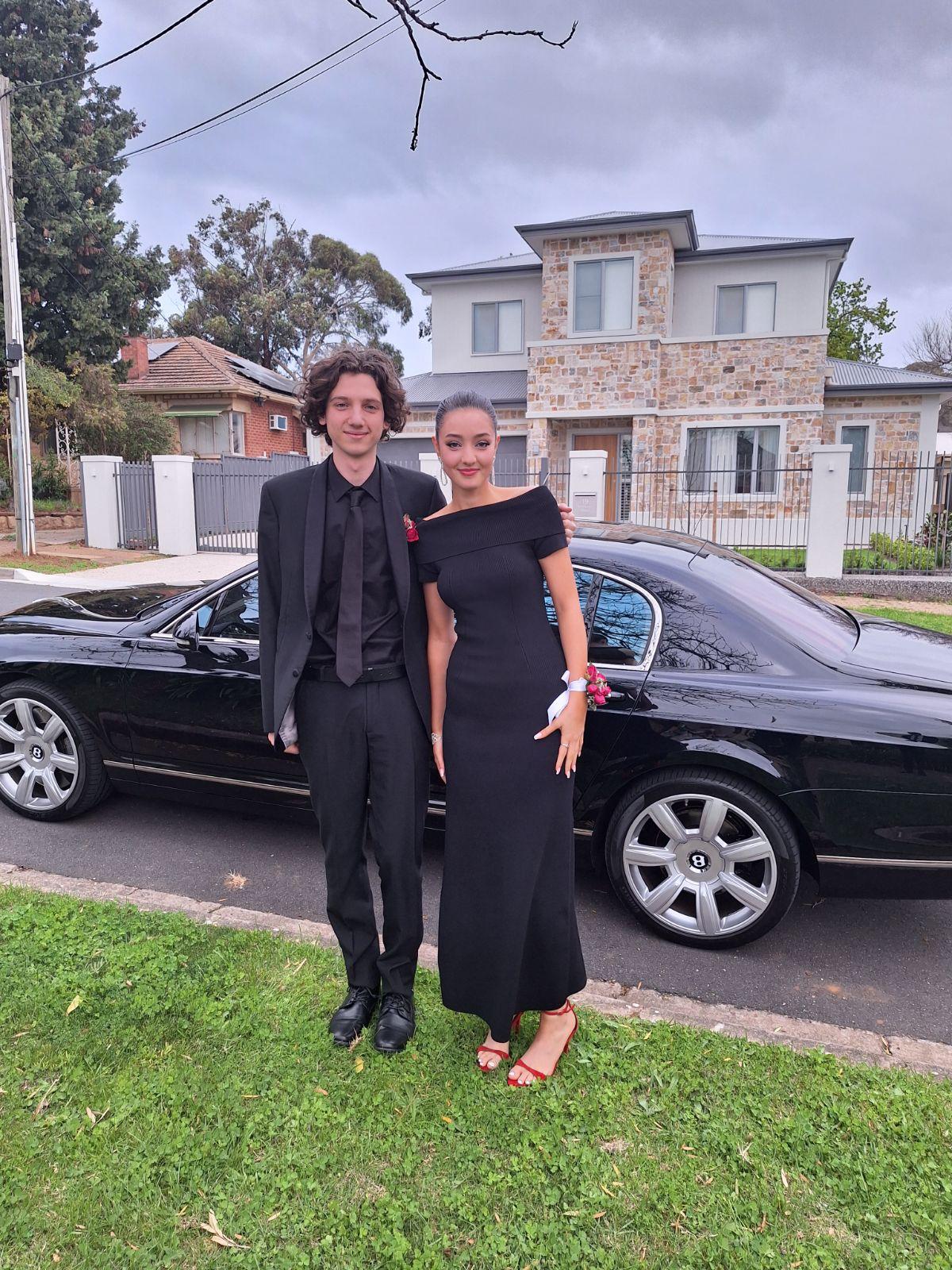 Graduation couple beside a black Mercedes